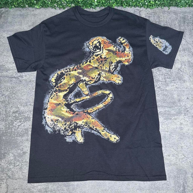 Black white wolf graphic tee flat lay on concrete with grass above