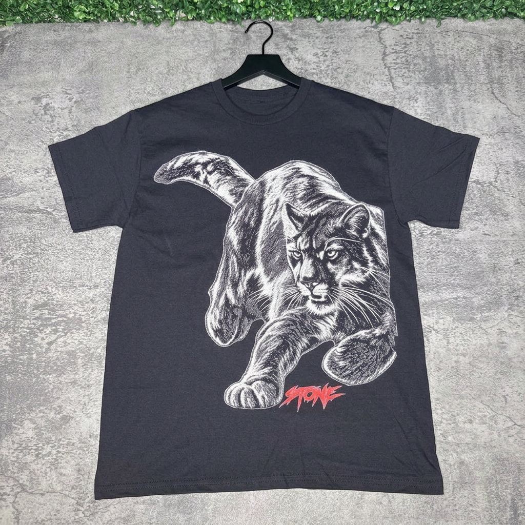 Black STONE panther tee on a hanger against gray concrete with green grass above