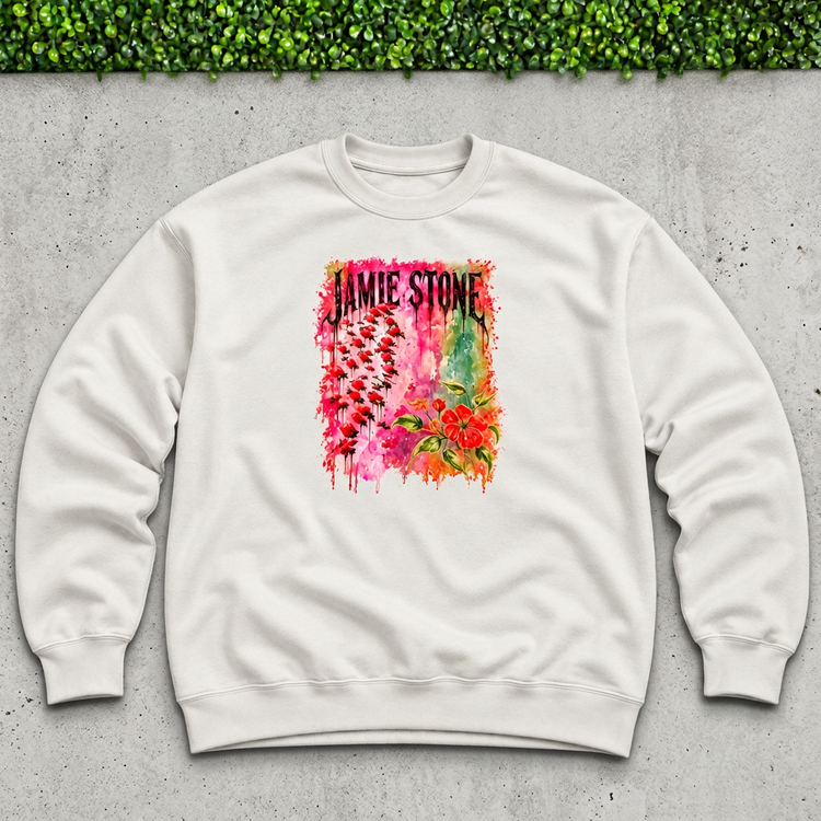 White Jamie Stone floral sweatshirt flat lay on concrete with a thin strip of green grass