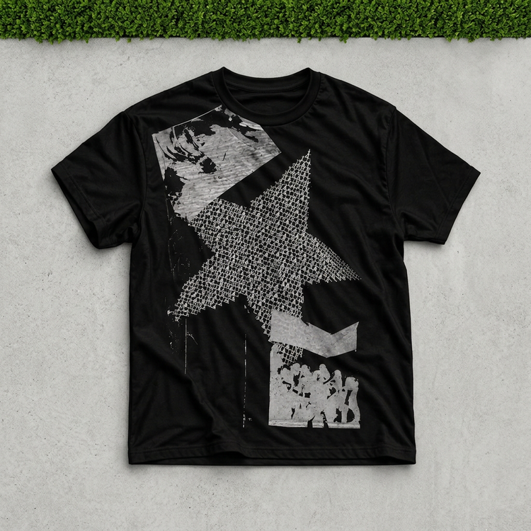 Black star collage tee flat lay on gray concrete with a thin green grass strip