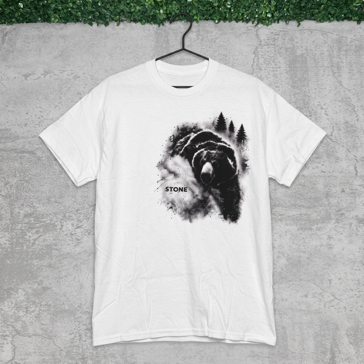 White STONE forest bear tee on a black hanger against gray concrete with grass above