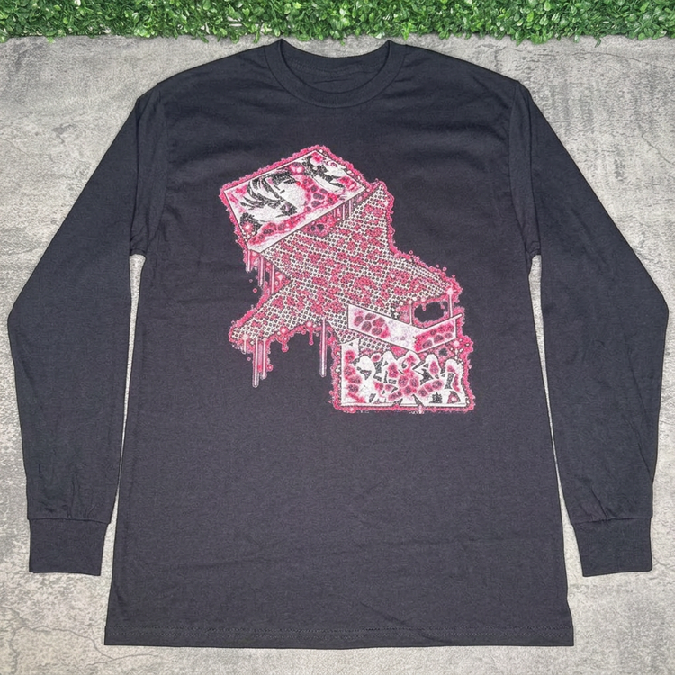 Black pink star collage long-sleeve tee laid flat on gray concrete with green grass above