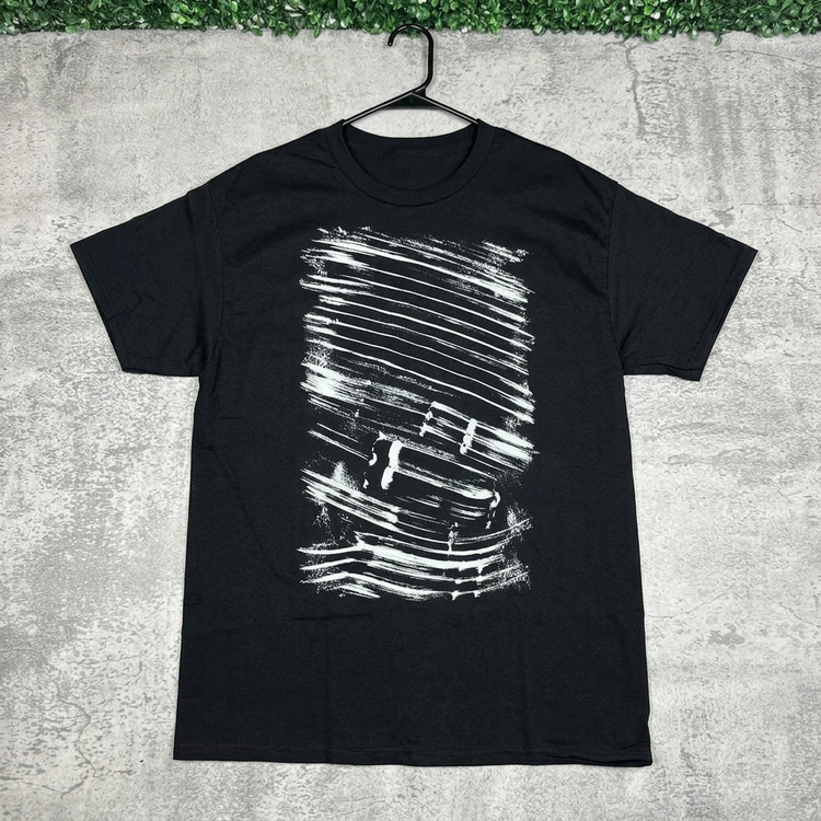 Black distressed brushstroke tee on a hanger against concrete with green grass above