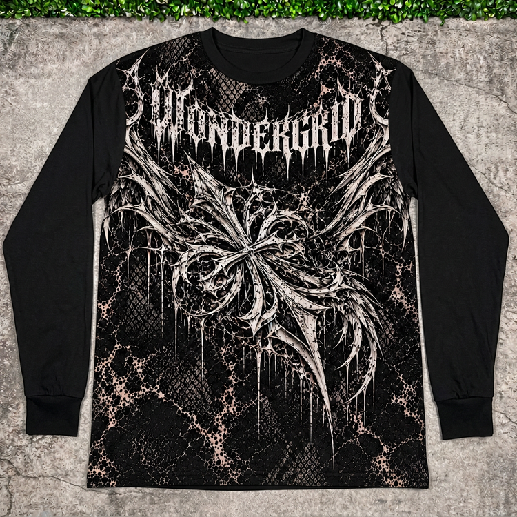 Black Winged Crest long sleeve flat lay on concrete with grass above