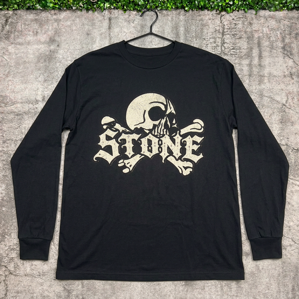 STONE skull long-sleeve tee on a hanger against concrete with grass above