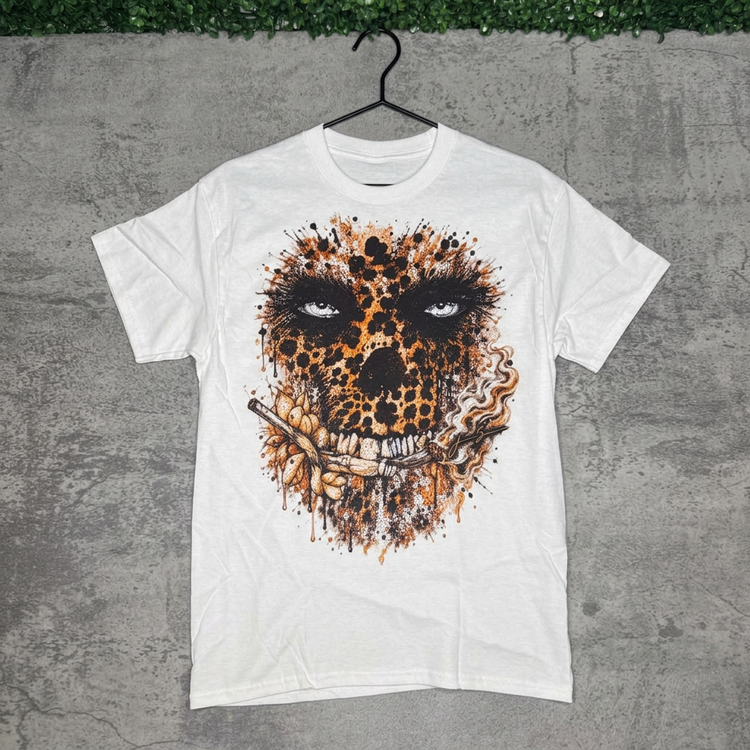 White leopard skull tee hanging against gray concrete with green grass along the top