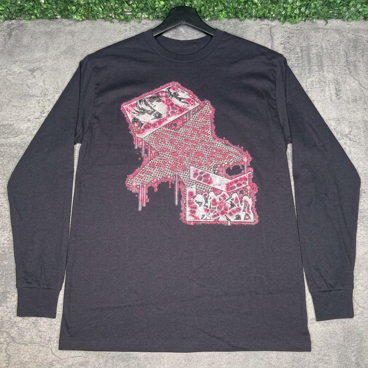 Pink star collage black long-sleeve tee on a black hanger against gray concrete with green grass above
