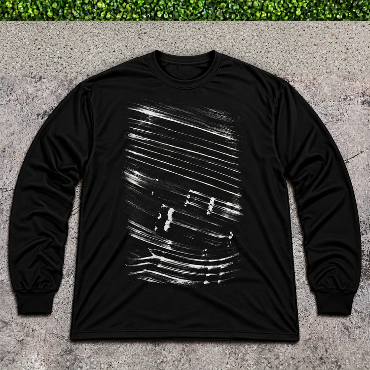 Black brushstroke long-sleeve shirt flat lay on light gray concrete with a thin strip of green grass above
