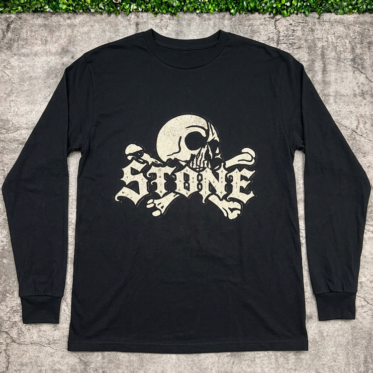 STONE skull long-sleeve tee flat lay on concrete with grass above